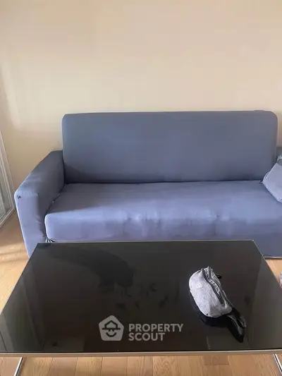 Modern living room with sleek black glass coffee table and comfortable blue sofa.