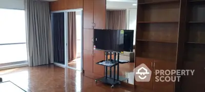 Spacious living room with wooden cabinets and TV stand, featuring elegant curtains and polished wooden floors.