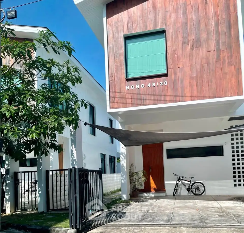 Modern townhouse with wooden facade and bike-friendly driveway in a sunny neighborhood.