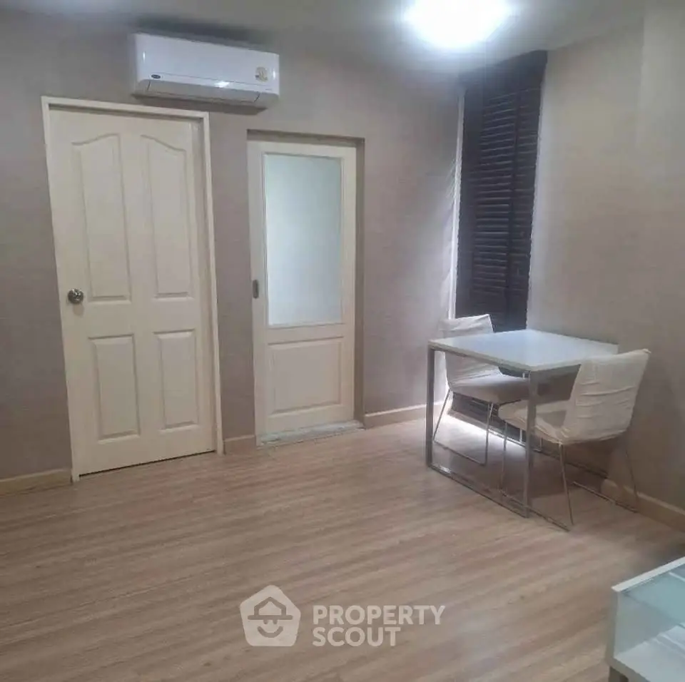 Cozy minimalist room with wooden flooring, modern dining set, and air conditioning.