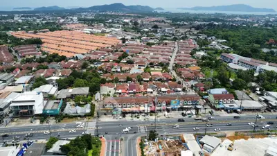 Aerial view of suburban neighborhood with rows of houses and a busy main road.