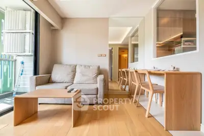 Modern living room with cozy sofa and dining area, featuring wooden flooring and natural light.