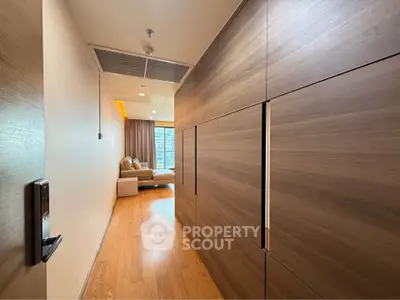 Modern apartment hallway leading to a cozy living room with wooden flooring and stylish decor.