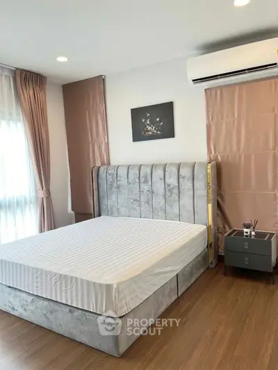 Modern bedroom with plush bed and elegant decor, featuring natural light and stylish furnishings.