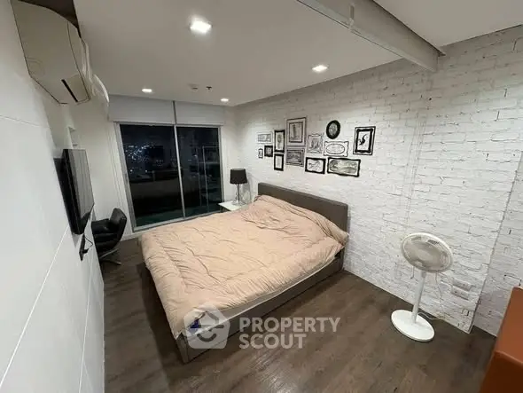 Modern bedroom with stylish decor and city view from balcony, featuring cozy bed and wall art.