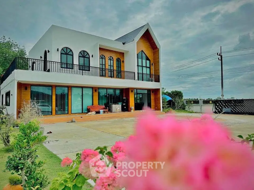 Stunning modern two-story house with large windows and lush garden, perfect for luxurious living.