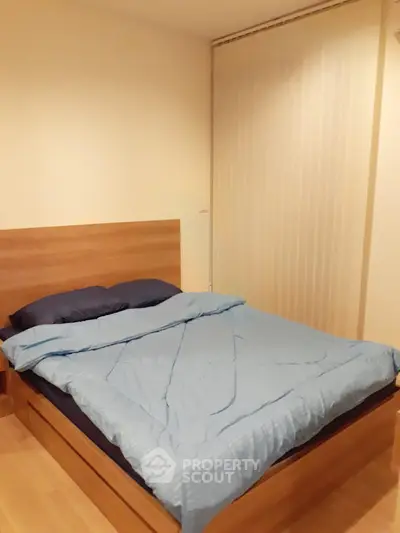 Cozy bedroom with wooden bed frame and blue bedding, perfect for restful nights.
