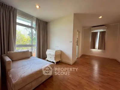 Spacious living room with elegant wooden flooring and large windows offering natural light.