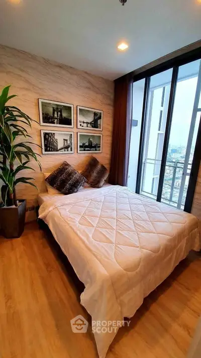 Cozy bedroom with large windows and city view, featuring stylish decor and comfortable bedding.
