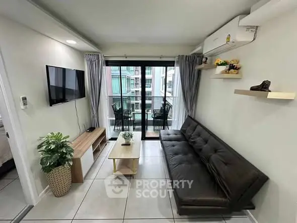 Modern living room with balcony access, sleek furniture, and natural light.