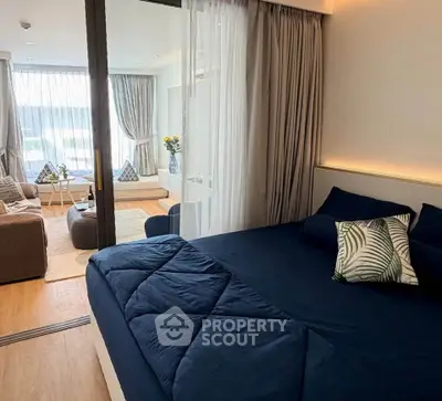 Modern bedroom with cozy living area and large windows in stylish apartment.