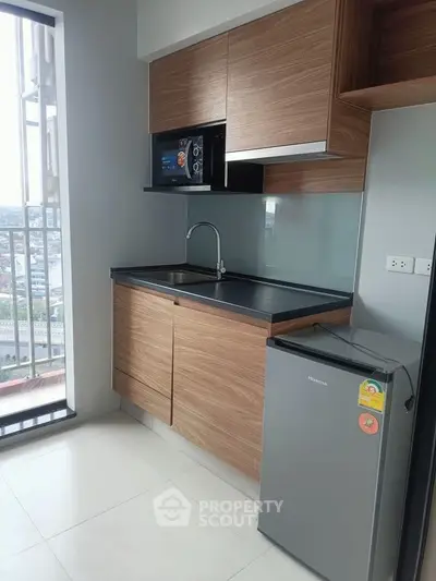 Modern kitchen with sleek cabinets and compact fridge in high-rise apartment.