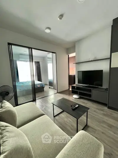 Modern living room with sleek design and view into cozy bedroom