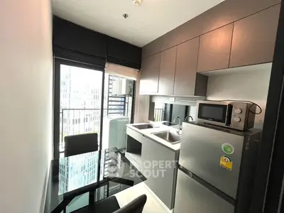 Modern kitchen with sleek cabinetry and city view from window, featuring stainless steel appliances and glass dining table.