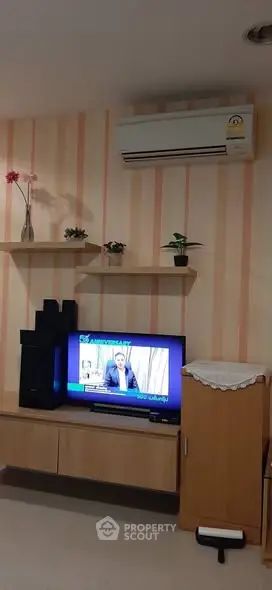 Cozy living room with modern TV setup and air conditioning, perfect for relaxation.