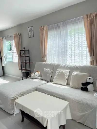 Cozy living room with plush sofa and natural light, perfect for relaxation.