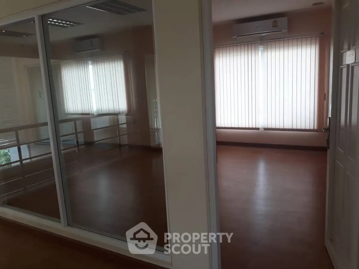 Spacious room with large windows and wooden flooring, ideal for versatile use.