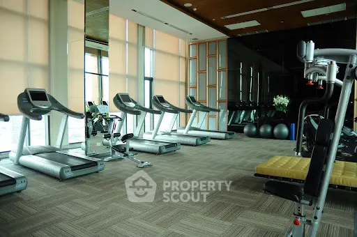Spacious modern gym with treadmills and fitness equipment in luxury building.