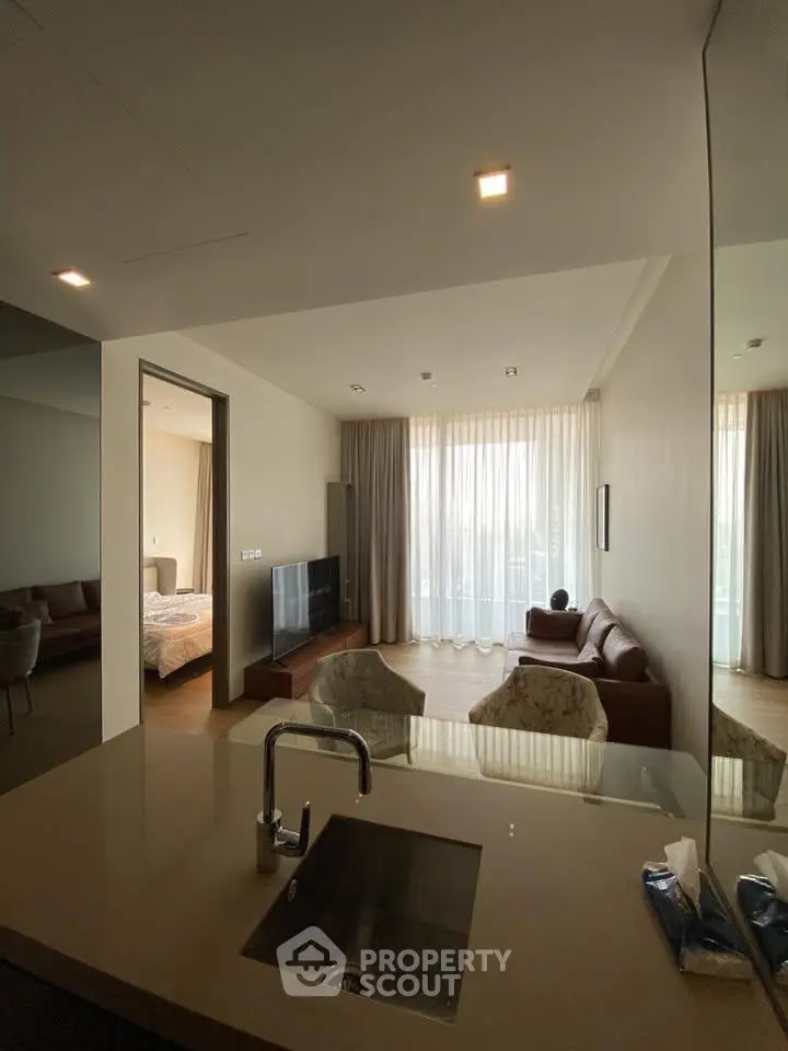 Modern open-plan living room with kitchen island and large windows in a stylish apartment.