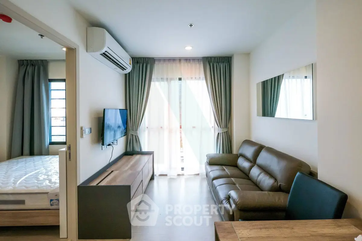 Modern living room with leather sofa, wall-mounted TV, and large window with curtains