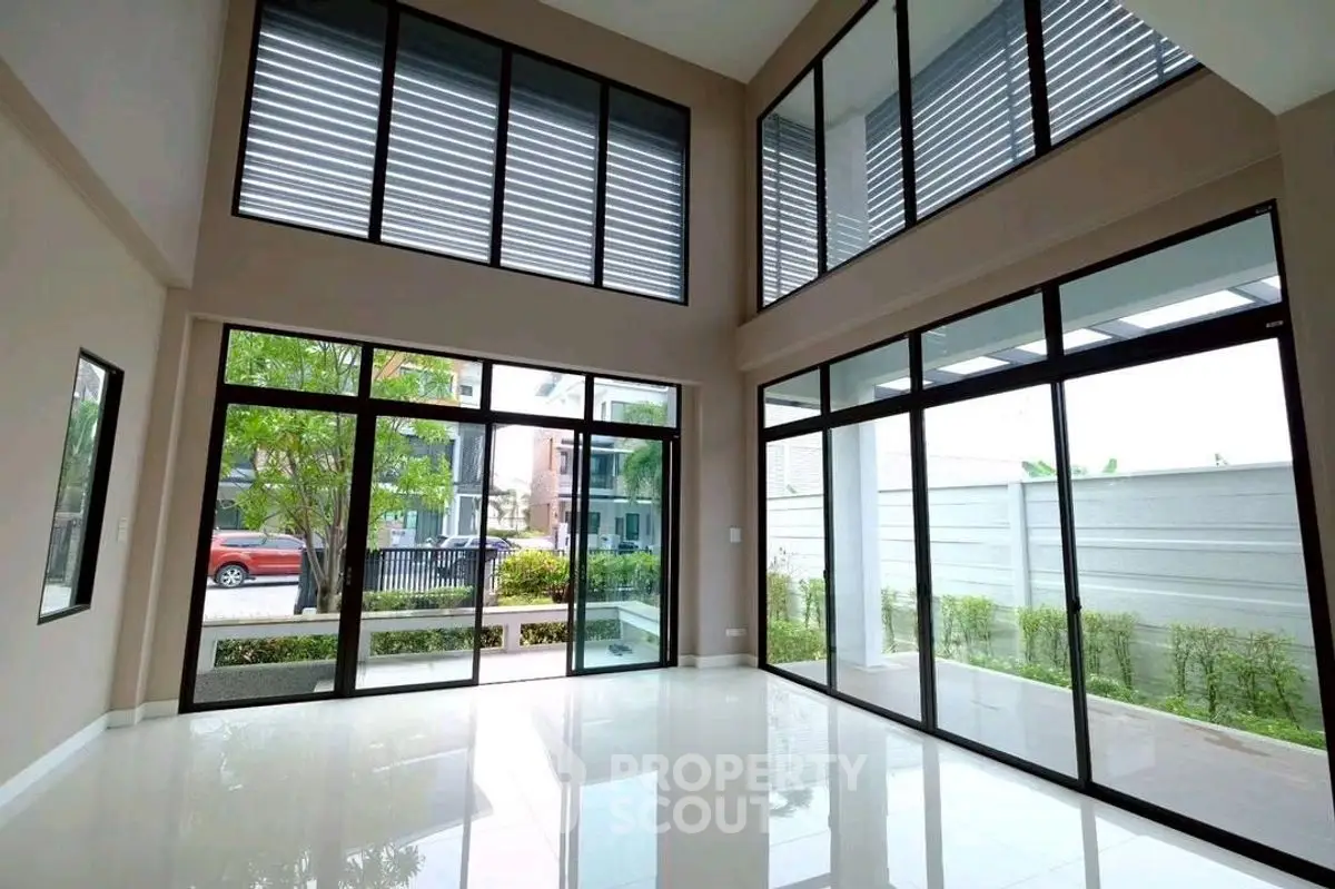 Spacious modern living room with floor-to-ceiling windows and garden view.
