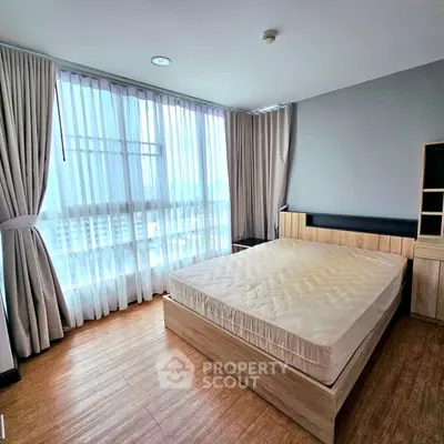 Spacious bedroom with large windows and modern furnishings in a high-rise apartment.