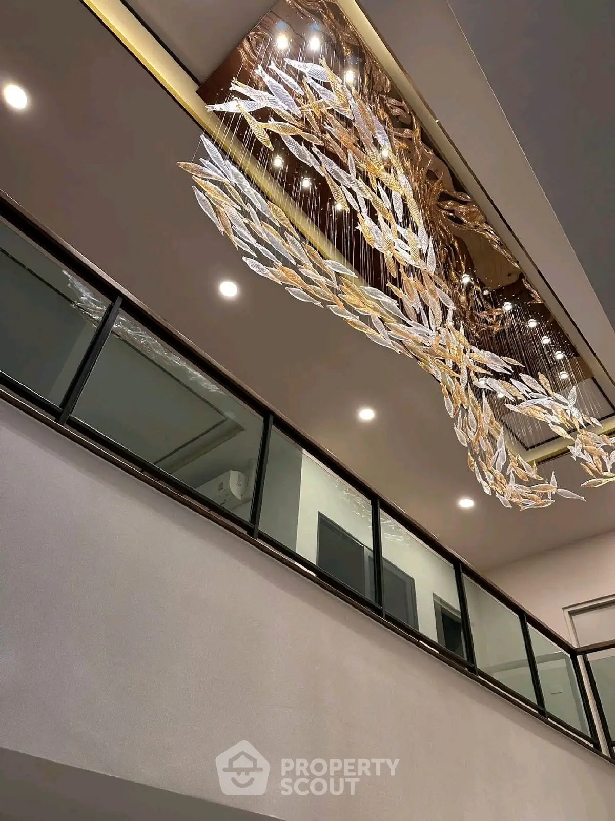 Luxurious modern interior with stunning chandelier and glass railing, showcasing elegance and sophistication.