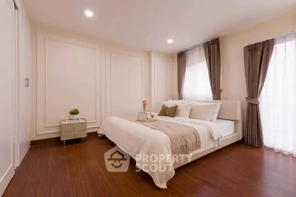 Elegant bedroom with cozy decor and natural light, featuring a stylish bed and wooden flooring.