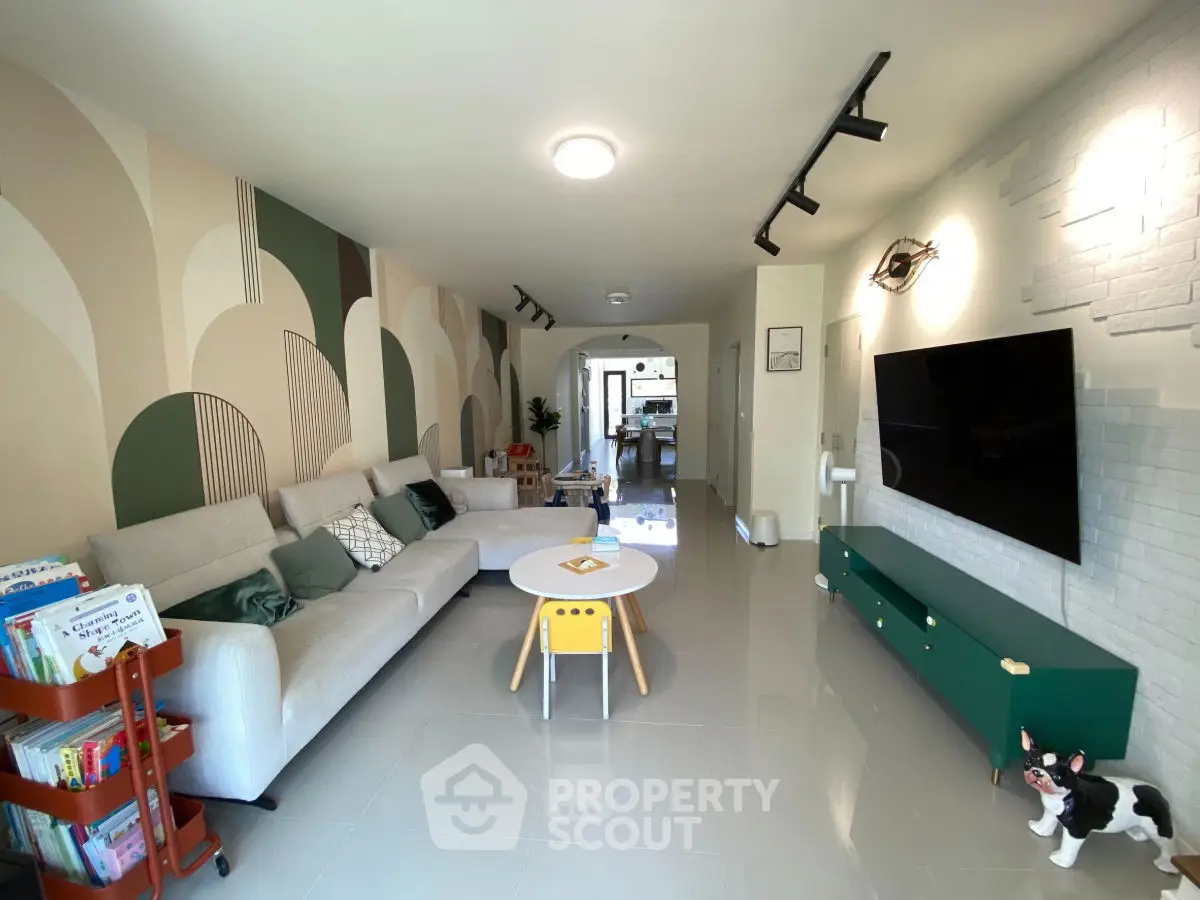 Modern living room with stylish decor and spacious layout, featuring a large sofa and wall-mounted TV.