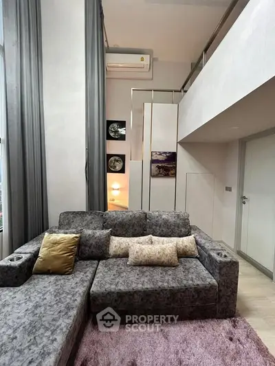 Modern living room with stylish grey sofa and high ceilings in a contemporary apartment.