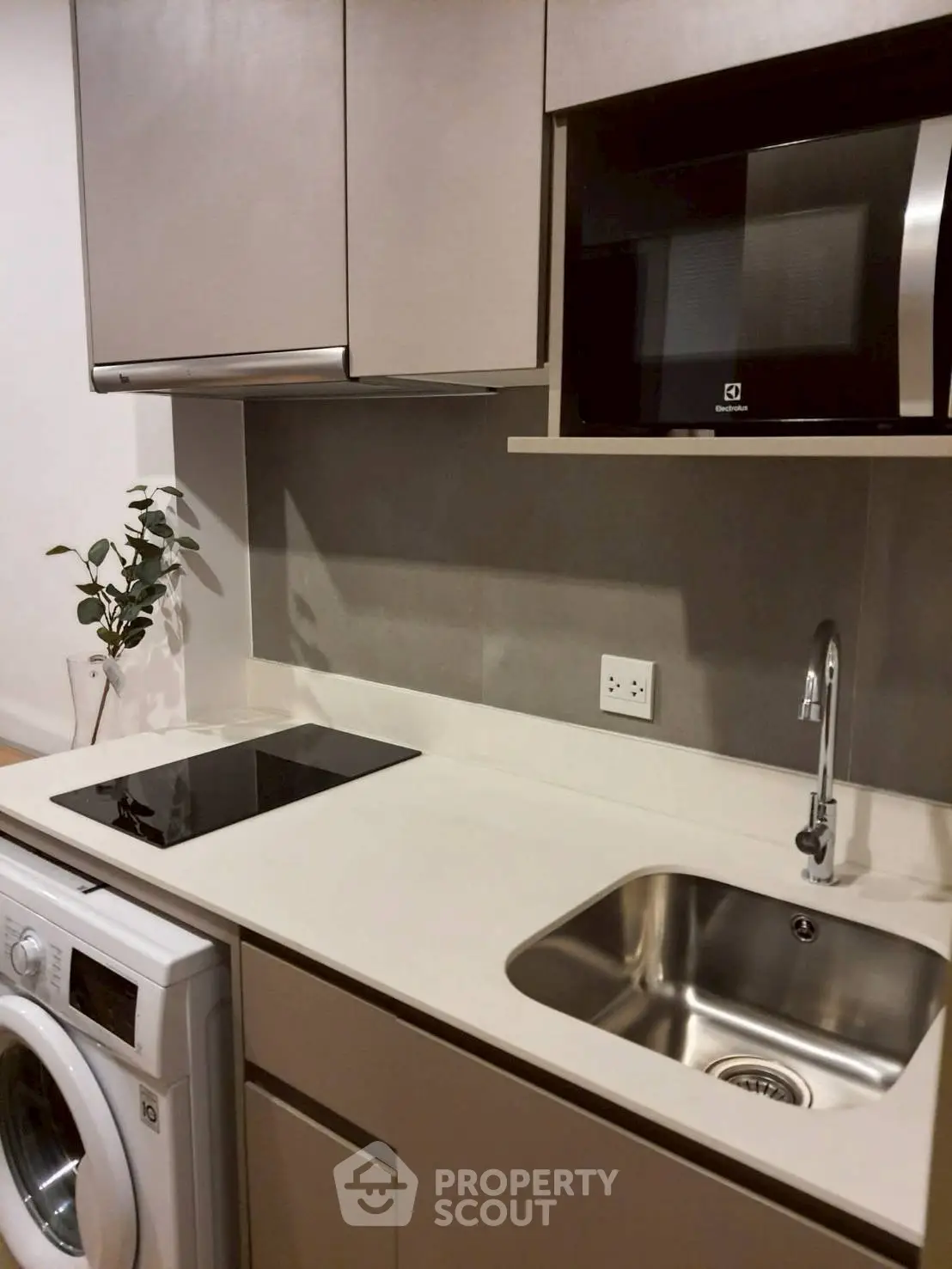 Modern kitchen with sleek appliances and compact design, featuring a washing machine and microwave.