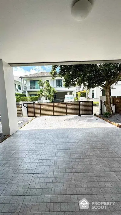 Spacious driveway with modern tiled flooring and gated entrance in a suburban neighborhood.