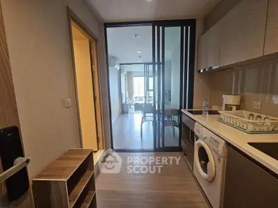 Modern kitchen with washing machine and open layout leading to living area