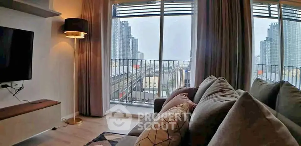 Modern living room with cozy sofa and city view from large windows in high-rise apartment.