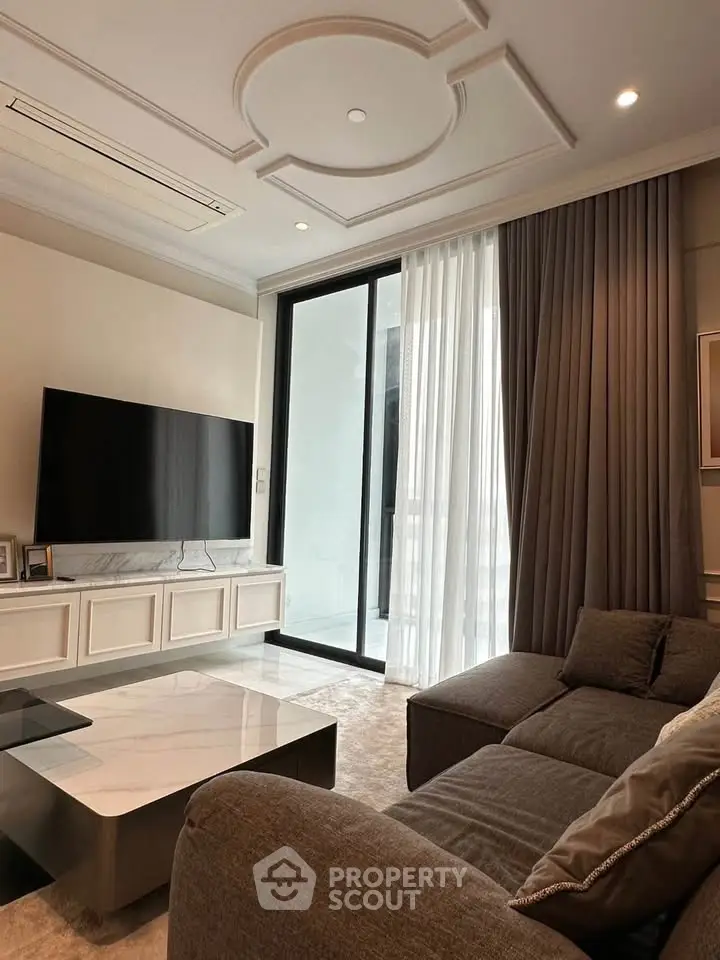 Luxurious living room with modern decor and large TV, featuring elegant ceiling design and floor-to-ceiling curtains.