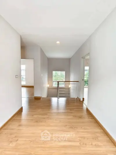 Spacious hallway with wooden flooring and natural light in modern home
