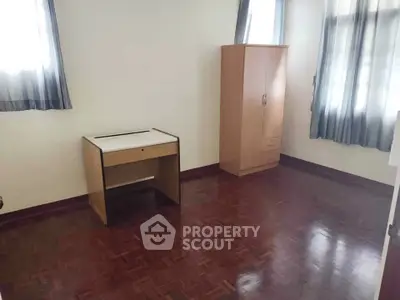 Spacious bedroom with wooden flooring and natural light