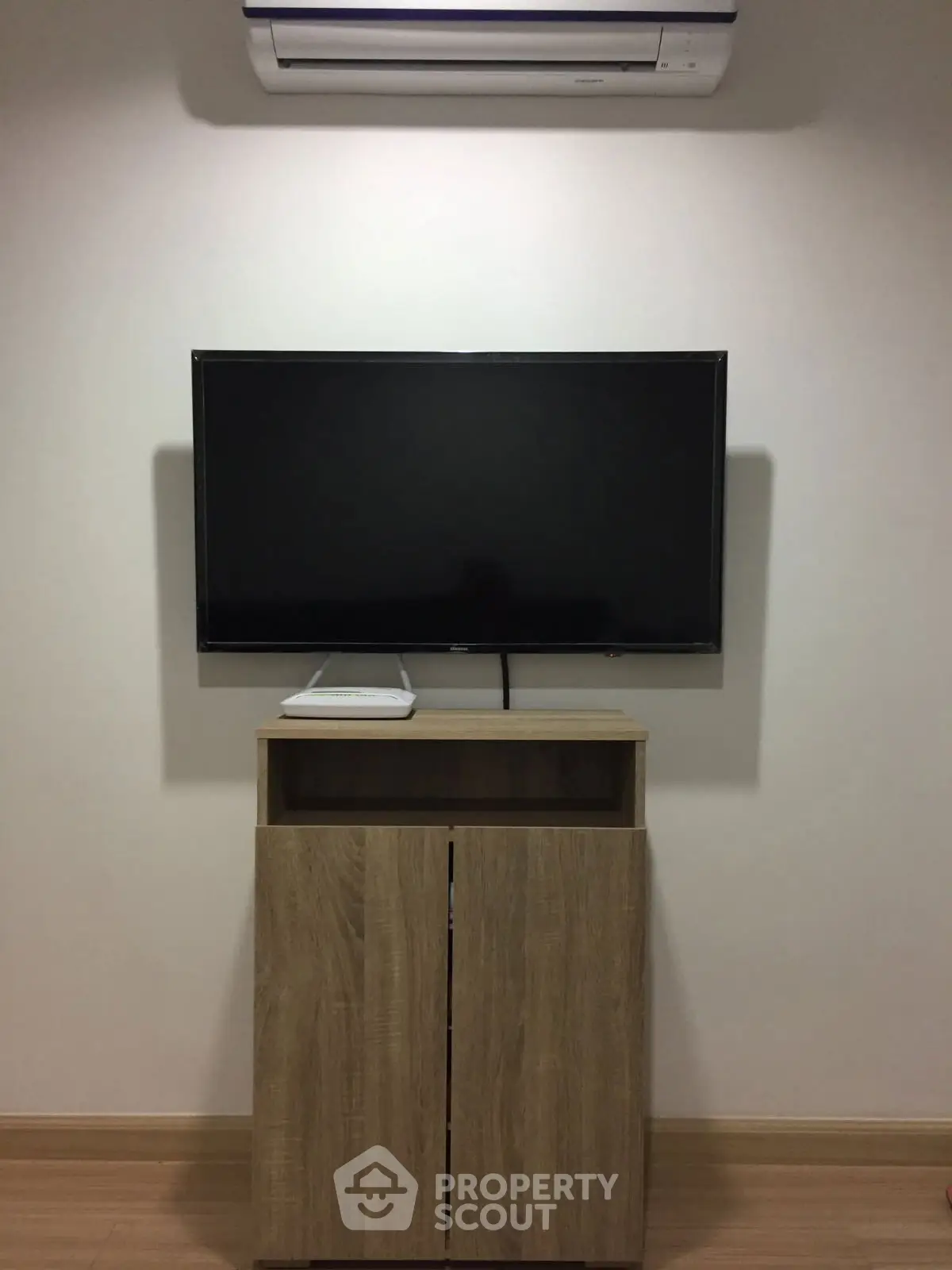 Modern living room with sleek TV setup and air conditioning unit.