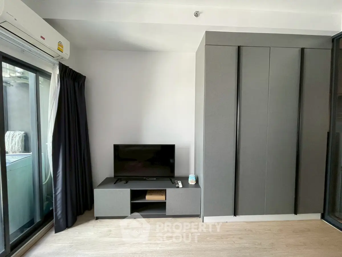 Modern living room with sleek TV stand and large wardrobe, featuring a balcony view.