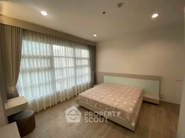 Spacious bedroom with large window and modern decor