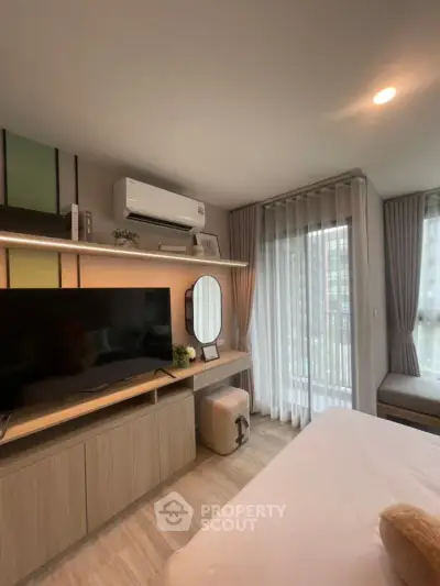 Modern bedroom with TV, air conditioning, and large window with sheer curtains.
