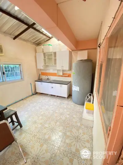 Charming fixer-upper kitchen with vintage tile flooring, ample natural light, and classic white cabinetry, awaiting your personal touch to transform into a culinary haven.