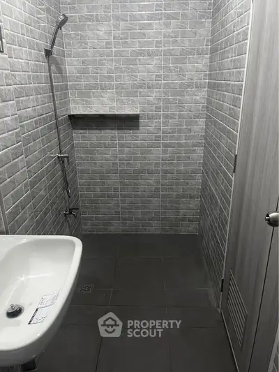 Modern minimalist bathroom with sleek gray tiles and a compact sink.