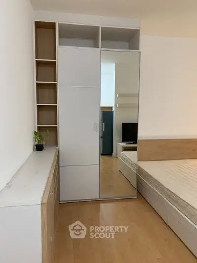 Modern bedroom with mirrored wardrobe and wooden flooring