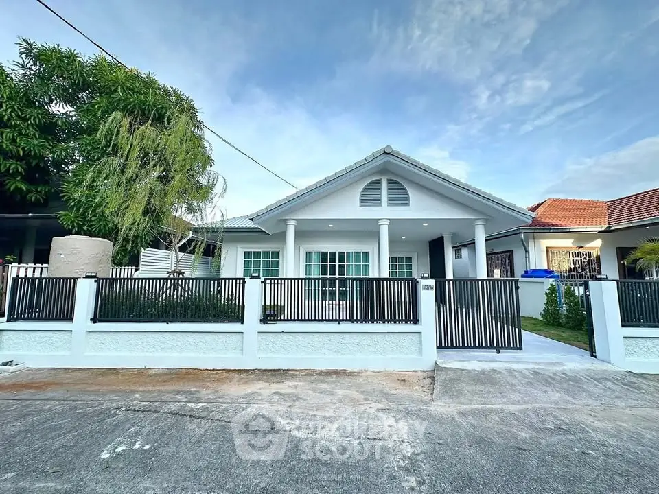 Charming single-story house with modern fence and lush greenery