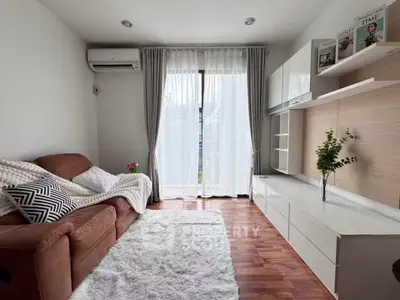 Charming living room with cozy sofa, elegant curtains, and stylish shelving in a bright, airy space.