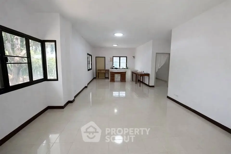 Spacious open-plan living room with large windows and tiled flooring in a modern home.