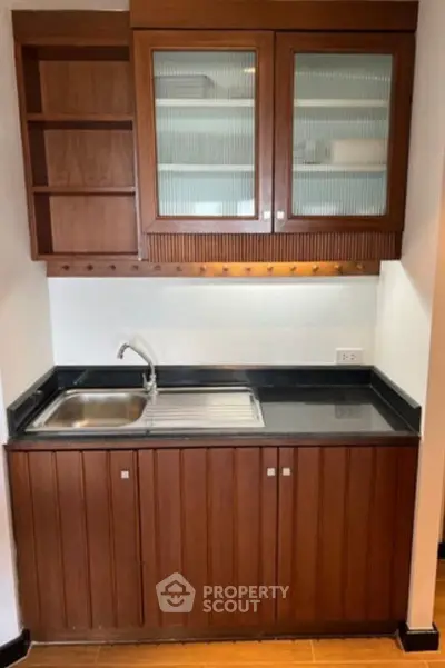 Charming compact kitchen with wooden cabinets and sleek countertop