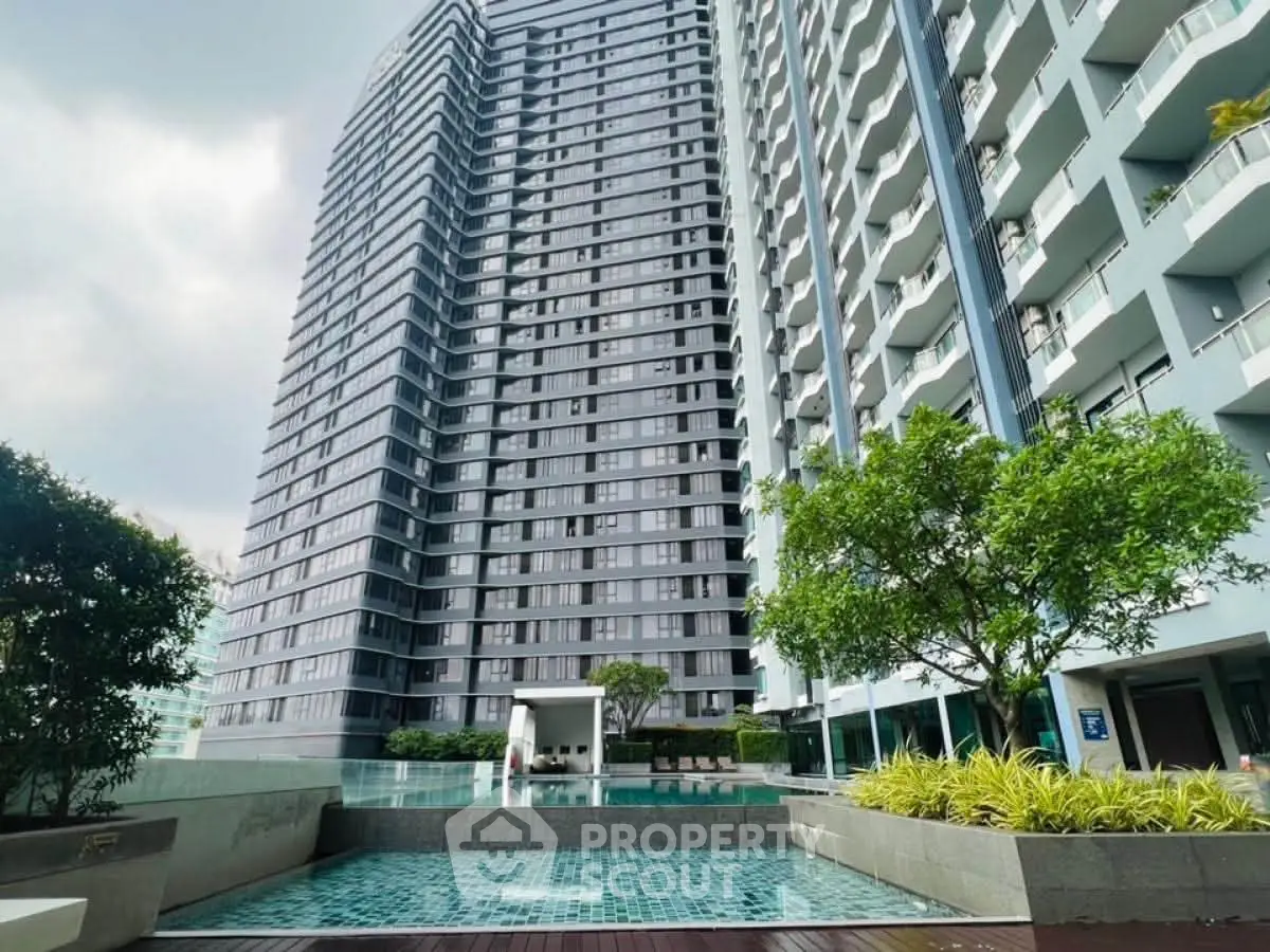 Modern high-rise building with pool and lush greenery, perfect for urban living.