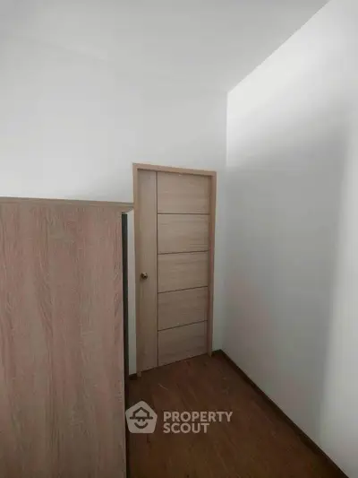 Minimalist small room with wooden flooring and modern door design.